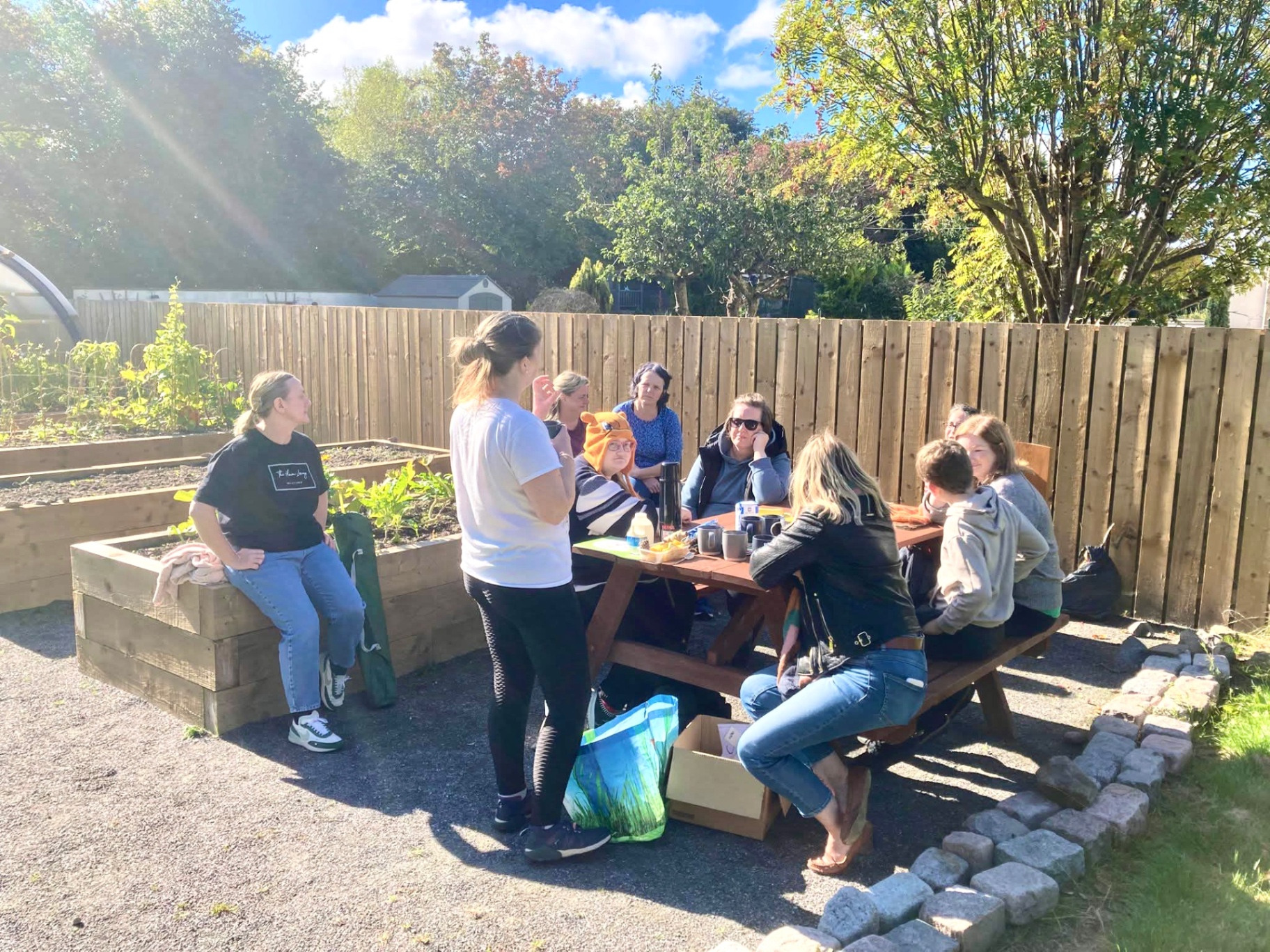 A small group enjoying a therapeutic gardening workshop together in a sunlit community garden